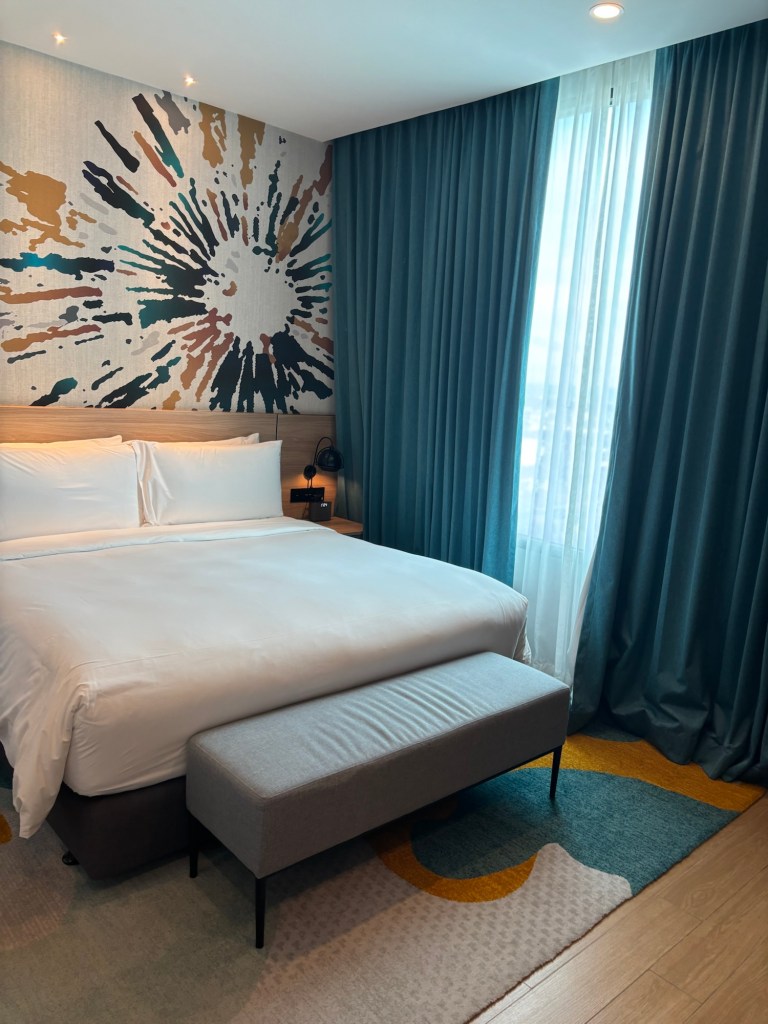 King‑size bed in the master bedroom of a two‑bedroom suite at Holiday Inn & Suites Siracha Laemchabang, featuring contemporary décor, soft lighting, and premium bedding.