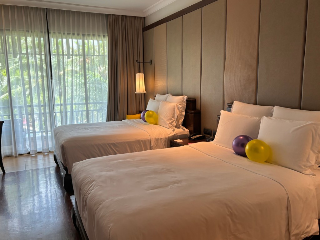 Twin Queen beds with premium linens, wooden furnishings, and garden‑view balcony at InterContinental Pattaya Resort in Thailand.